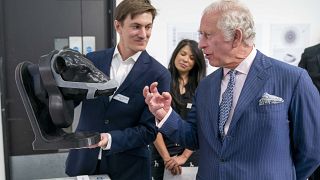 Britain's King Charles looks at a wearable device for cattle to neutralise their methane emissions in real time created by design group Zelp.