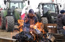 A farmer sits next to a fire during a gathering near the highway junction in Melegnano, near Milan, Italy, Wednesday, 7 February, 2024.