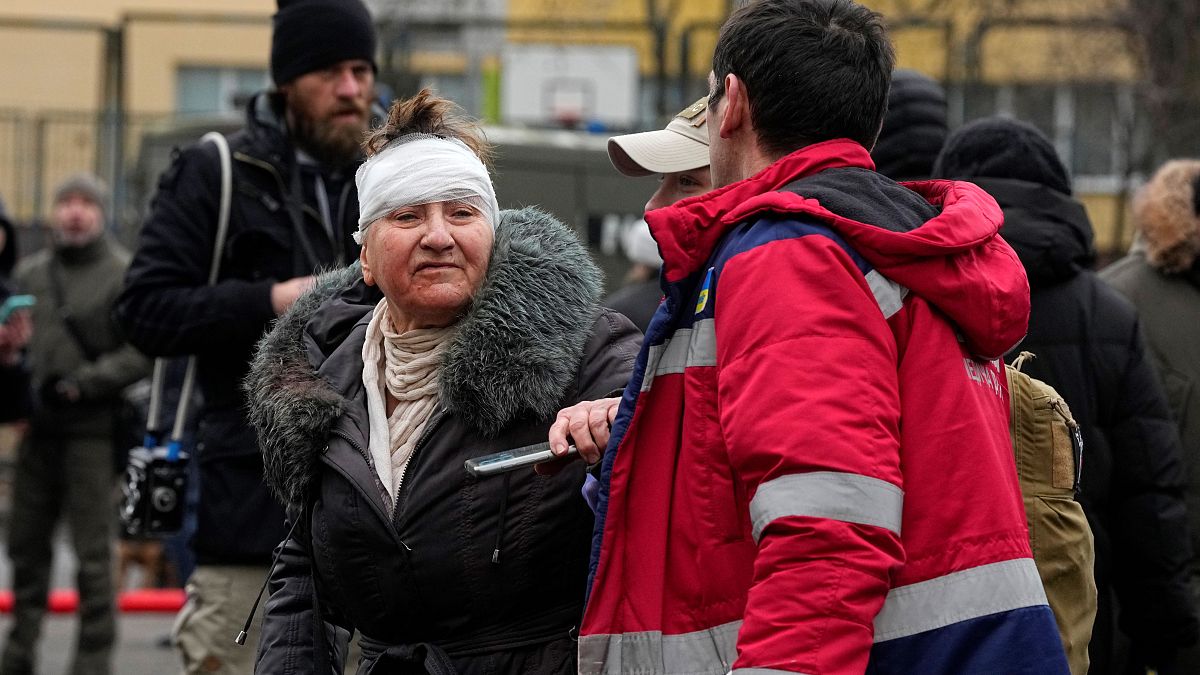 Медики помогают женщине, пострадавшей в результате российского обстрела