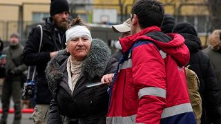 A medical worker helps a woman in a yard of an apartment building destroyed after Russian attack in Kyiv, Ukraine, Wednesday, Feb. 7, 2024. 