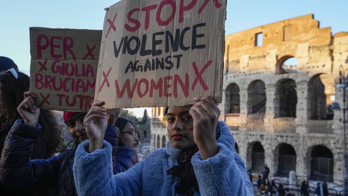 Женщина держит плакат с надписью "Остановите насилие в отношении женщин" во время демонстрации в Международный день борьбы за ликвидацию насилия в отношении женщин, Рим