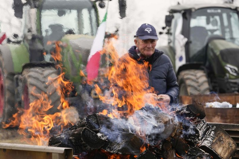 Ein Bauer sitzt neben einem Feuer während einer Demonstration in der Nähe des Autobahnkreuzes in Melegnano nahe Mailand, Februar 2024