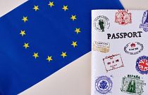 علم الاتحاد الأوروبي إلى حانب يافطة كتب عليها باسبور وعليها بعد الطوابع التي تمثل الدول الأعضاء