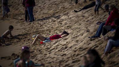 A woman sunbathes at a beach in Barcelona, Spain, Sunday, Feb. 4, 2024. Spain's weather agency says it experienced abnormally high temperatures for this time of year.