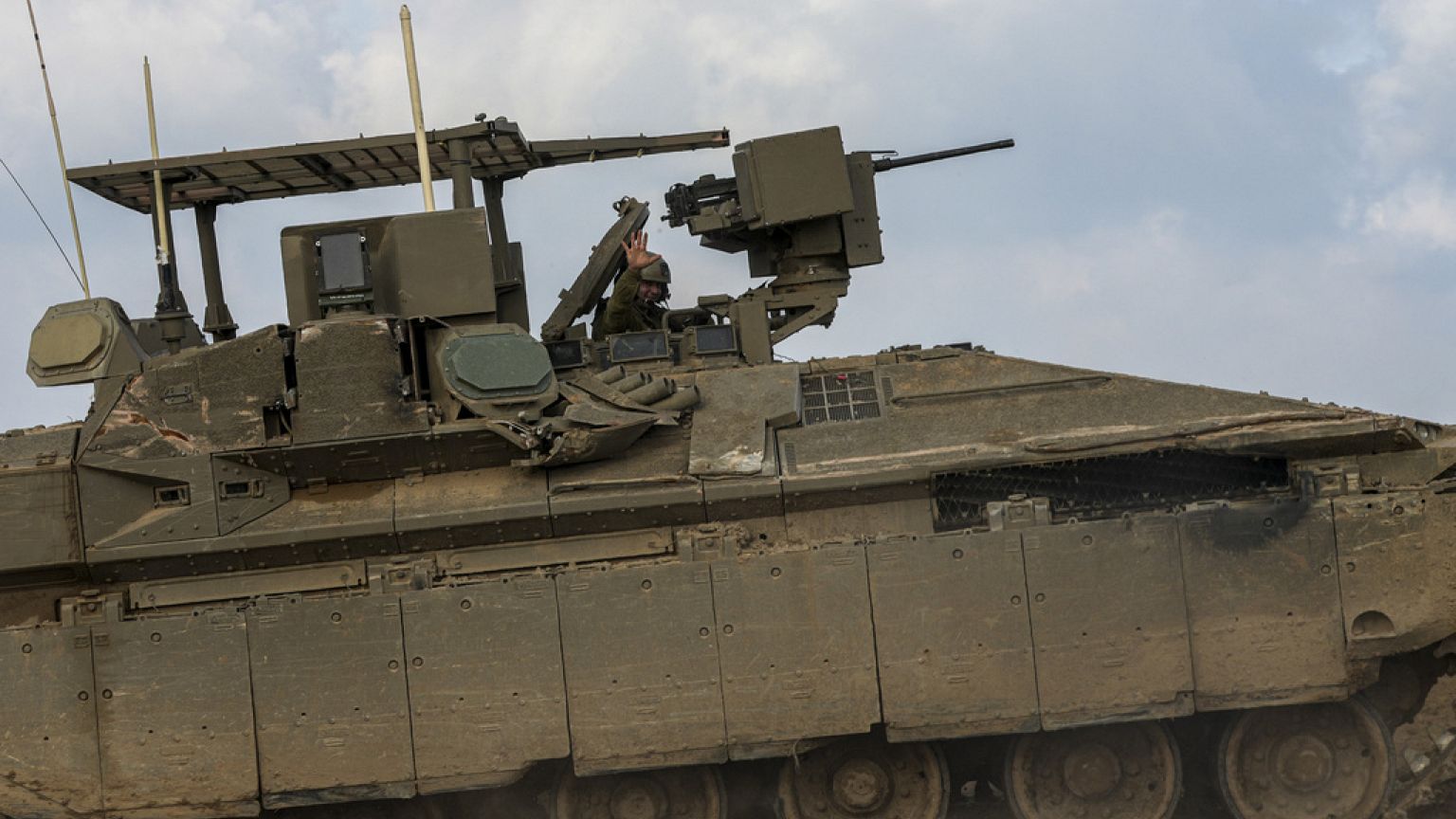 An Israeli soldier waves as he drives near the border with the Gaza Strip, as seen in southern Israel, Tuesday, Feb. 6, 2024. 
