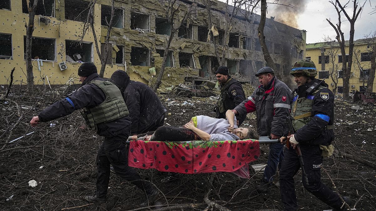 Украинские сотрудники МЧС и полиции эвакуируют раненую беременную женщину из роддома, пострадавшего от российского авиаудара, в Мариуполе, Украина, 9 марта 2022 года.
