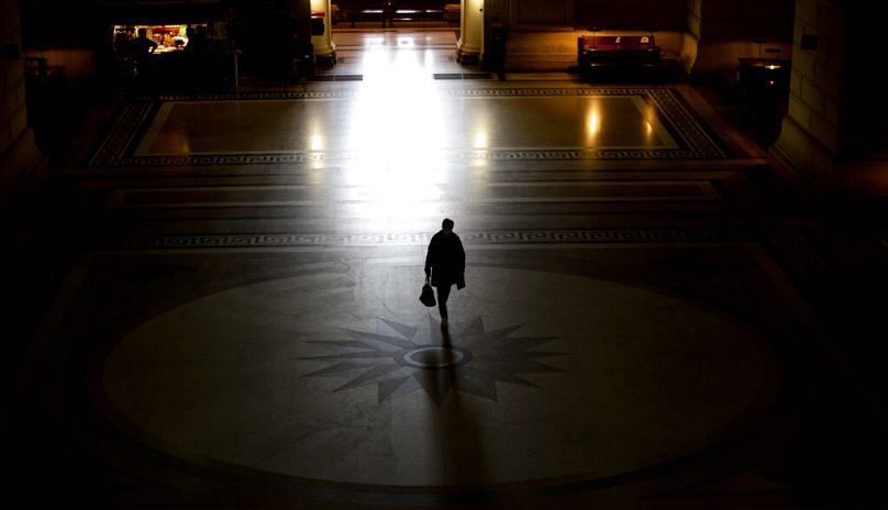 A woman walks past a news stand in the main lobby of the Justice Palace in Brussels, May 2021