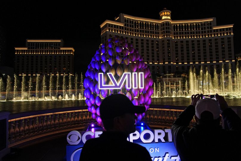 People stand by signage for the Super Bowl as the Bellagio fountains erupt along the Las Vegas Strip ahead of the Super Bowl