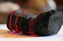 Herculaneum scroll with red laser lines being scanned at Institut de France by Brent Seales and his team