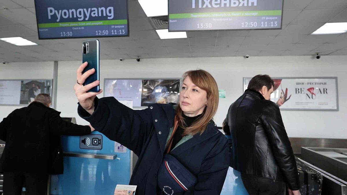 Um turista russo tira uma selfie depois de fazer o check-in para embarcar num avião com destino à Coreia do Norte, no aeroporto internacional de Vladivostok, sexta-feira, 9 de fevereiro de 2024