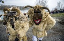 Hombres con disfraces y máscaras llegan desde una isla al otro lado del río Danubio en Mohács, Hungría, para participar en el tradicional desfile de carnaval de la ciudad.