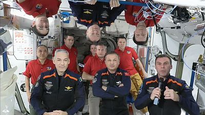 The 11 International Space Station crew members representing Expedition 70 (red shirts) and Axiom Space 3 (dark blue suits) crews gather for a farewell ceremony.