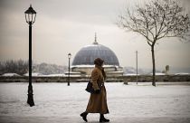 سيدة تركية تسير وسط الثلوج في مدينة إسطنبول وتظهر قبة مسجد السليمانية. يناير 2022