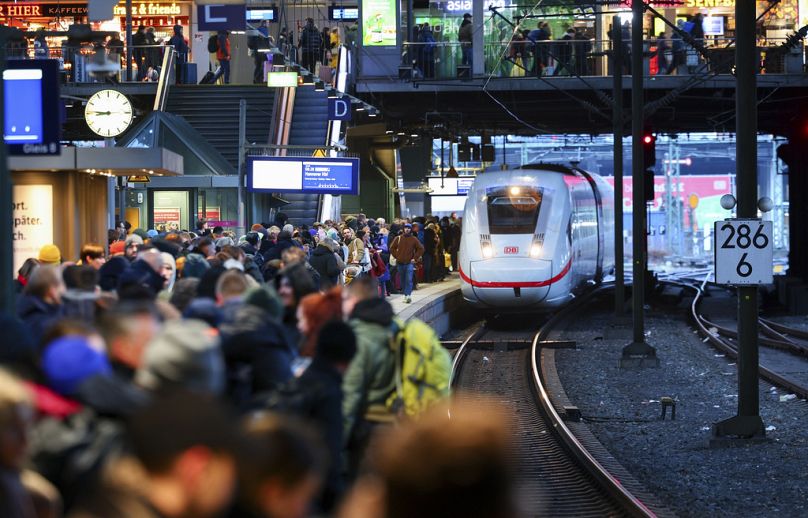 Numerous travelers wait for their train on a full platform at the main station in Hamburg, December 2023