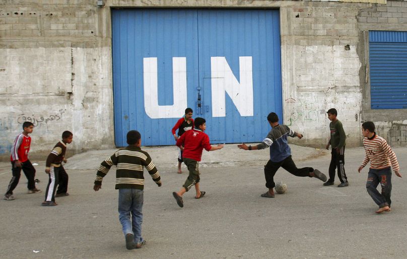 Des enfants palestiniens jouent au football devant la porte d'un centre de distribution alimentaire des Nations Unies dans la ville de Gaza, février 2009