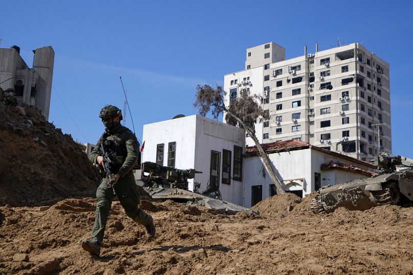 An Israeli soldier runs down a crater-like hole giving way to a small tunnel entrance into UNRWA compound, in Gaza, February 2024