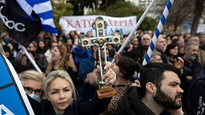 متظاهرة يونانية تحمل صليباً