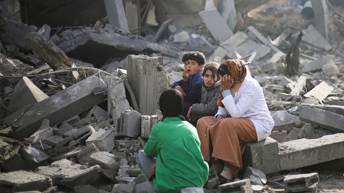 Palestinians sit by the destruction from the Israeli bombardment of the Gaza Strip in Rafah on Monday, Feb. 12, 2024. 