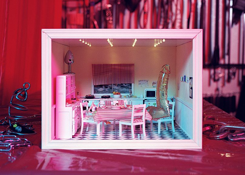 In this photo, Szombat staged her subject's dollhouse to represent a toxic relationship she escaped from, before becoming a dominatrix.