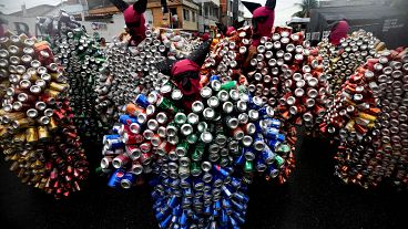 محتفلون يرتدون أزياء مصنوعة من البيرة وعلب الصودا يشاركون في موكب الكرنفال في شارع "بلوكو دا لاتينها" في مادري دي ديوس