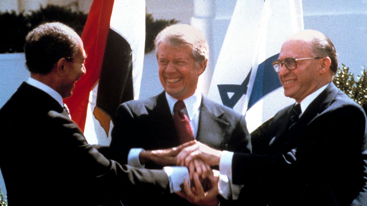 رئیس جمهور مصر انور سادات، سمت چپ، رئیس جمهور ایالات متحده، جیمی کارتر، وسط و مناخیم بگین، نخست وزیر اسرائیل، در حالی امضای معاهده صلح بین مصر و اسرائیل، واشنگتن ۱۹۷۹