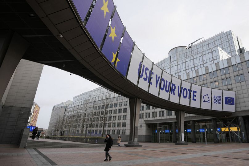 A woman walks under a banner advertising the European elections outside the European Parliament in Brussels, Januar 2024