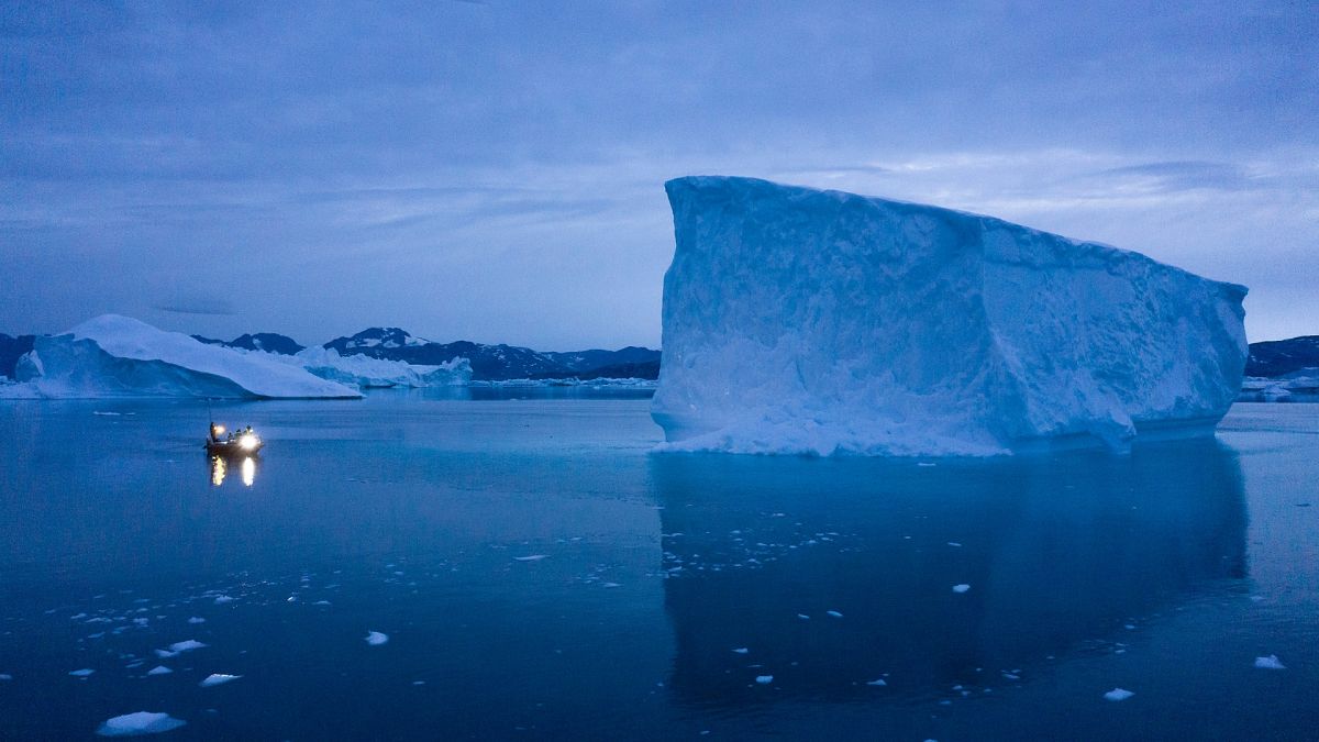  Un bateau navigue de nuit à proximité de grands icebergs dans l'est du Groenland. 