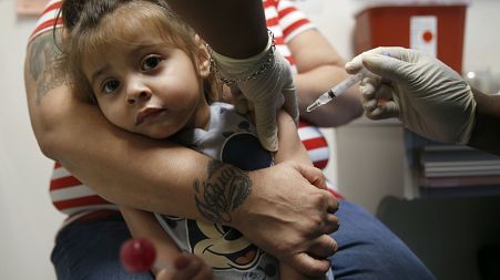 In a Friday, March 8, 2019 photo, Karma Islas, 2, is held by her mother Maria Islas of Dallas as she gets a shot for a vaccine administered by Demetria McRuffin, RN.