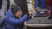 Люди скорбят над гробами семьи, погибшей в результате пожара, вызванного ударом российского беспилотника по их дому в жилом квартале в Харькове, Украина, 12 февраля