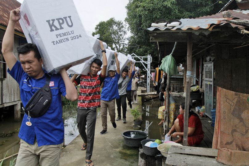 Electoral workers carry ballot boxes during the distribution of election paraphernalia to remote villages, in Pemulutan, South Sumatra, February 2024