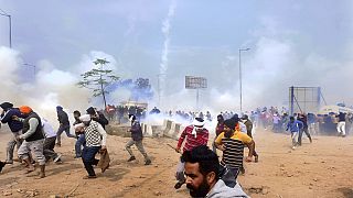 Farmers run for cover after police fired tear gas to disperse protesting farmers who were marching to New Delhi near the Punjab-Haryana border at Shambhu, India, Tuesday, Feb.