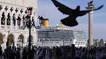 In this file photo, a cruise ship passes by St. Mark's Square filled with tourists, in Venice, Italy