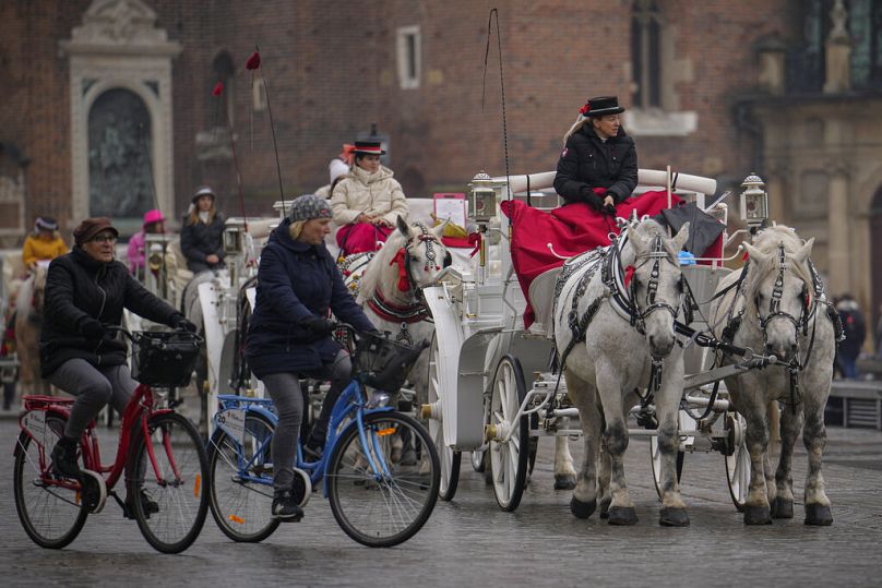 Horse pulled carts wait for customers in the 13th century main square in Krakow, November 2022