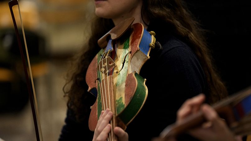 A woman member of the 'Sea Orchestra' rehearses with violin made from the wood of wrecked immigrants' boats in Milan, northern Italy, Saturday, Feb. 10, 2024.