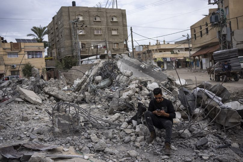 Ibrahim Hasouna, center, the sole survivor among his family, sits amidst the debris of his bombed home in Rafah.