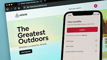 The login page for Airbnb's iPhone app is seen in front of a computer displaying Airbnb's website on May 8, 2021, in Washington. 