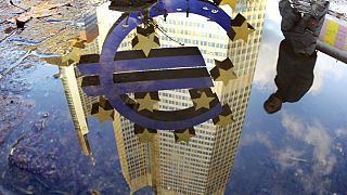 Σε αυτή τη φωτογραφία αρχείου της Πέμπτης 5 Ιανουαρίου 2012, ένα άτομο αντανακλάται σε μια λακκούβα δίπλα στο γλυπτό του ευρώ μπροστά από την Ευρωπαϊκή Κεντρική Τράπεζα στη Φρανκφούρτη της Γερμανίας.