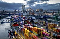 A container is loaded onto a cargo ship in the harbor in Frankfurt, Germany, Wednesday, Dec. 13, 2023. In background the European Central Bank. (AP Photo/Michael Probst)