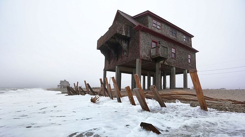 Houses resting on pylons are elevated above waves on the beach, 25 January 2024, in South Kingstown, RI.