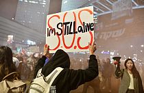 Még élek! - tartja magasba a táblát egy túszmentés párti tüntető