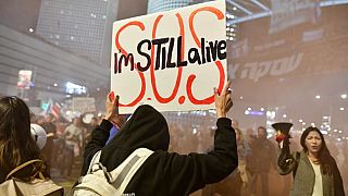 Még élek! - tartja magasba a táblát egy túszmentés párti tüntető