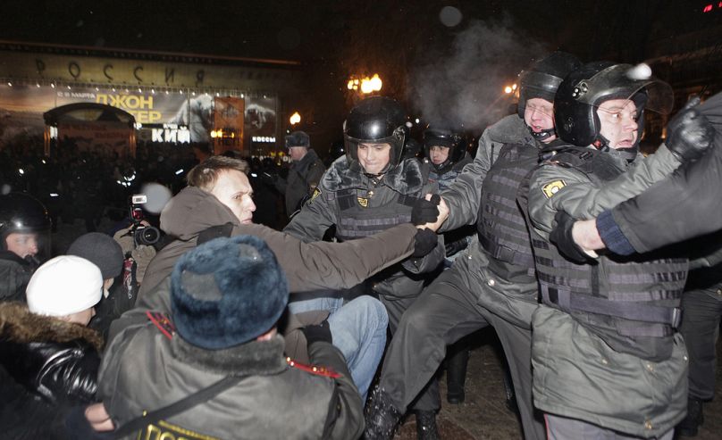 FILE - Police detain protest leader Alexei Navalny, seen wearing hooded jacket, after a rally in Pushkin Square in Moscow, Monday, March 5, 2012.