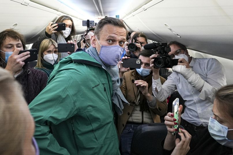 FILE - Alexei Navalny is surrounded by journalists on a plane before a flight to Moscow in the Berlin Brandenburg Airport, Jan. 17, 2021.