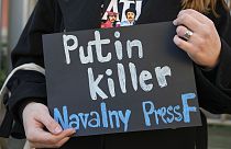 Sırbistan'ın başkenti Belgrad'da Rusya Büyükelçiliği önüne gelen bir protestocunun elinde taşıdığı pankartta 'katil Putin' yazısı yer alıyor