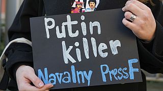 Sırbistan'ın başkenti Belgrad'da Rusya Büyükelçiliği önüne gelen bir protestocunun elinde taşıdığı pankartta 'katil Putin' yazısı yer alıyor