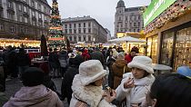 Des visiteurs mangent du gâteau de cheminée, un plat de fête traditionnel hongrois, sur l'un des marchés de Noël en plein air les plus célèbres d'Europe, le marché de l'Avent Bazilika, dans le centre de Budapest.