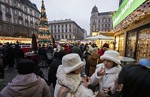 Os visitantes comem bolo de chaminé, um alimento festivo tradicional húngaro, num dos mercados de Natal ao ar livre mais famosos da Europa, o mercado Advent Bazilika, no centro de Budapeste.