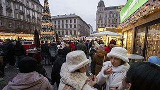 Des visiteurs mangent du gâteau de cheminée, un plat de fête traditionnel hongrois, sur l'un des marchés de Noël en plein air les plus célèbres d'Europe, le marché de l'Avent Bazilika, dans le centre de Budapest.