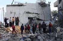 فلسطينيون ينظرون إلى الدمار الذي خلفته غارة إسرائيلية على مبنى سكني في رفح