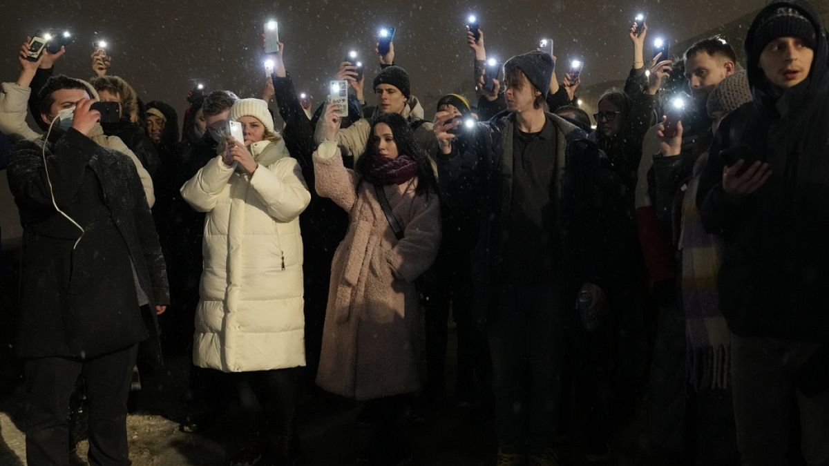 Varias personas sostienen sus teléfonos móviles en señal de homenaje a Alexéi Navalni en el Monumento a las Víctimas de la Represión Política, en San Petersburgo, Rusia.